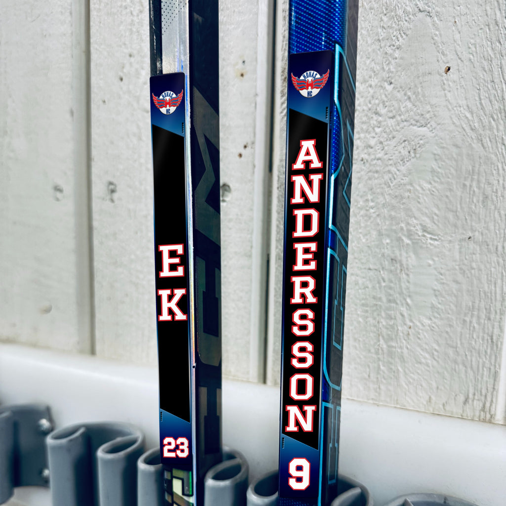 Hovås Hockey Club stick stickers applied to two hockey sticks in a rack