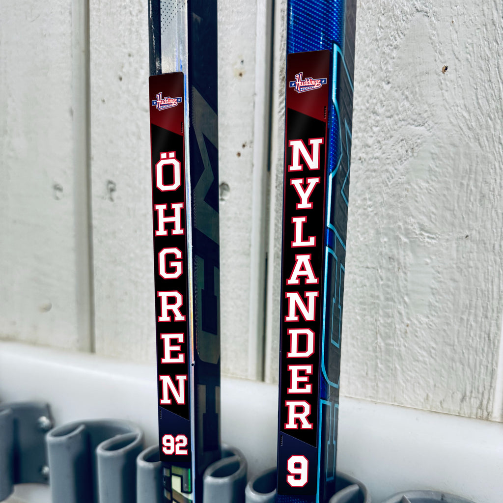 Huddinge Hockey stick stickers applied to two hockey sticks in a rack