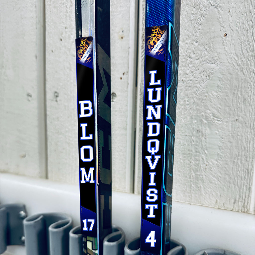 Saltsjöbaden stick stickers applied to two hockey sticks in a rack