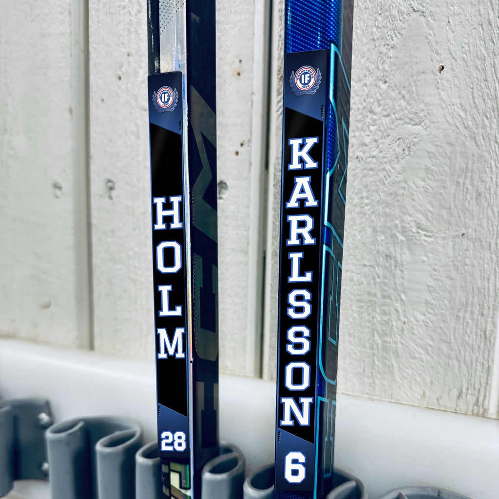 Trångsunds IF stick stickers applied to two hockey sticks in a rack