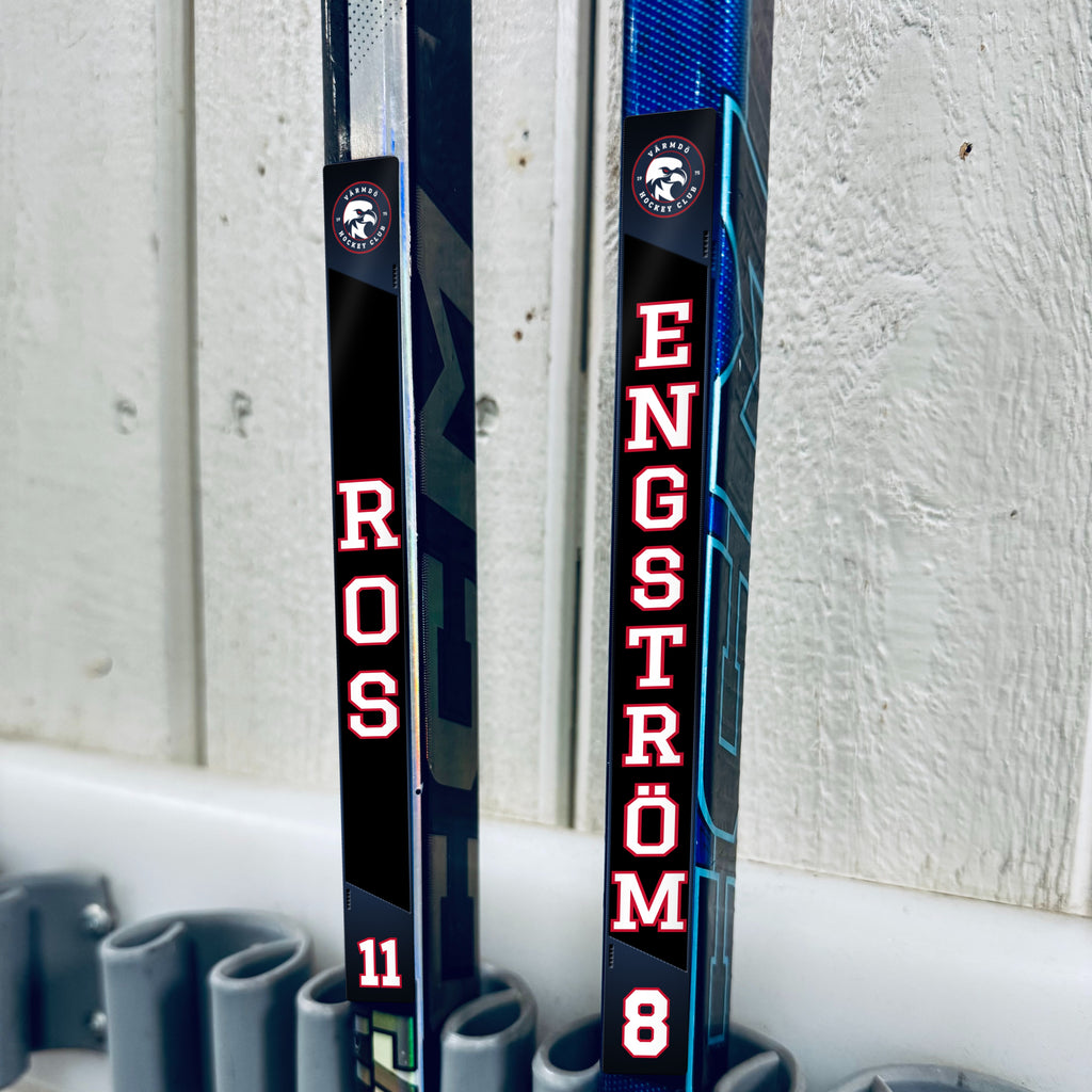 Värmdö Hockey stick stickers applied to two hockey sticks in a rack